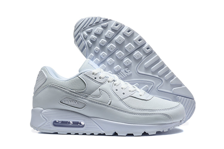 White Nike Air Max 90 sneakers shown from the side and with the outsole visible.