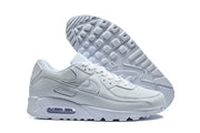 White Nike Air Max 90 sneakers shown from the side and with the outsole visible.