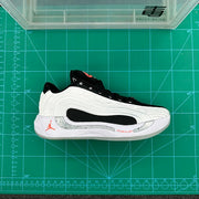 Opposite side view of a white and black Jordan low-top shoe on a green measurement mat.