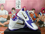Side view of white and purple Nike Kobe basketball shoes showing the swoosh and perforated panels