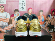 Rear view of gold and white basketball sneakers showing black collars, heel branding, white midsoles, and red outsole accents.