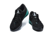 Pair of black low-top basketball shoes with green accents, shown from the front