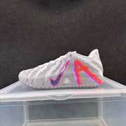 Side view of a white and gray Nike basketball shoe with orange, pink and blue details