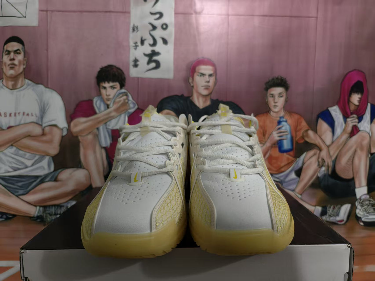 Pair of white Nike basketball sneakers with yellow and gold accents displayed from the front