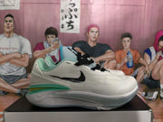 Side profile of a white Nike basketball sneaker with black Swoosh branding and layered turquoise-green midsole accents.