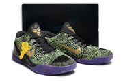 Pair of black, green, and purple basketball shoes with a dark box behind them.