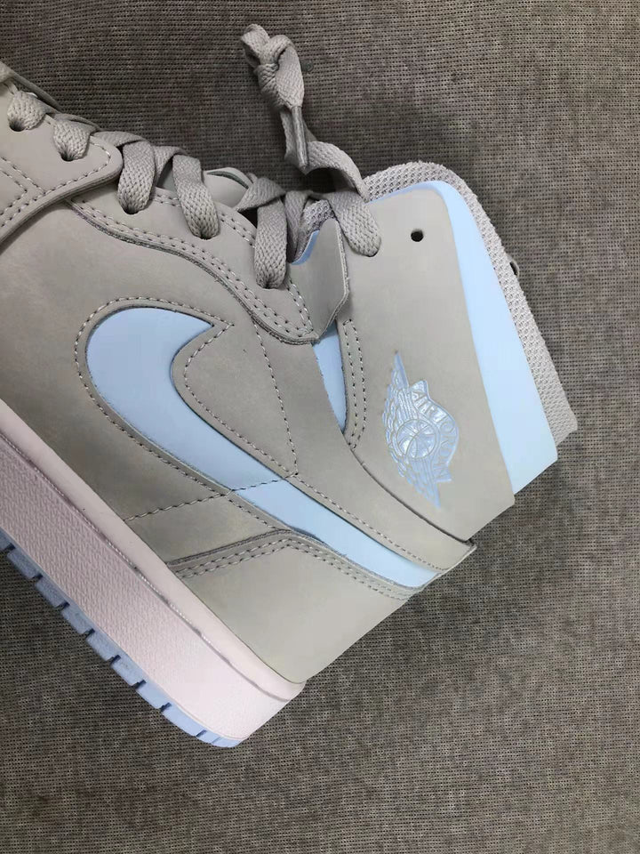 Close-up of the gray high-top sneaker showing the pale blue Swoosh, collar accent, laces, stitching, and ankle branding.