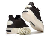 Black sneakers shown from the rear and sole, with visible adidas branding, cream outsoles, and coiled laces.
