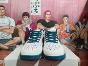Front view of white Nike basketball-style sneakers with dark blue laces, dark blue soles, and multicolor dotted detailing.