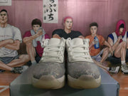 Front view of white and gray Jordan AJ-1 sneakers with patterned gray toe panels and translucent-tinted outsoles.