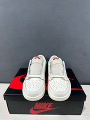 Front view of a pair of white low-top Jordan sneakers showing perforated toe boxes, padded tongues, and red tongue branding.