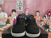 Front view of black Nike basketball sneakers showing black laces, purple tongue emblems, yellow side details, and white outsoles.