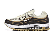 Side view of cream, black, and gold-tone Nike Air Max 97 OG sneakers.