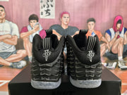 Rear view showing black heels with embroidered emblems and translucent speckled outsoles.