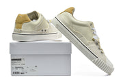 Cream and tan low-top sneakers displayed with a shoebox bearing Maison Margiela text.