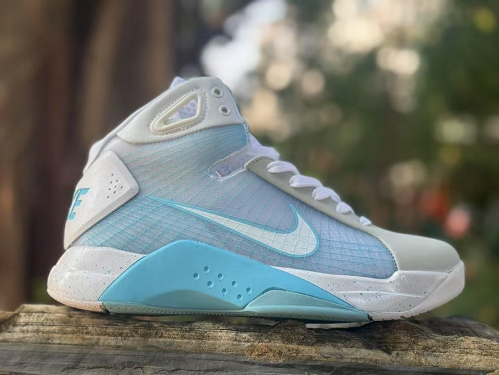 Side view of white and light blue Nike high-top basketball sneakers with a contrasting blue midsole section.