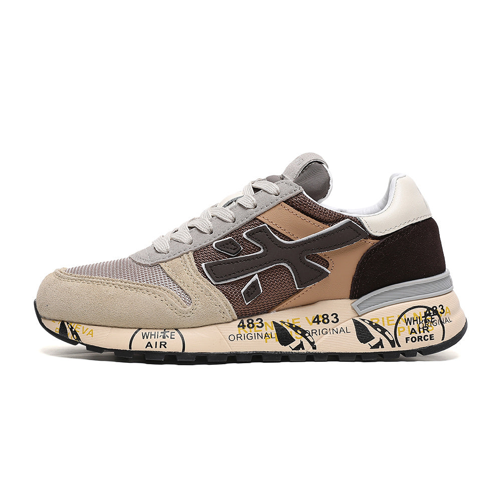 Side view of a brown, beige, and grey Premiata 483 low-top sneaker with lace-up closure and printed cream-colored sole.