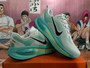 Angled view of two gray and green Nike running shoes showing the perforated uppers, black branding, and green sole units.
