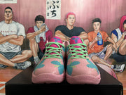 Front view of pink basketball shoes with teal and magenta patterned panels and bright green laces.