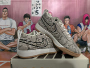 Angled view of a pair of gray patterned Nike Book 1 sneakers with black Swooshes, white midsoles, and gum-colored outsoles.