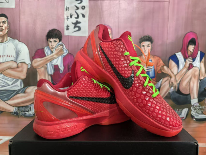 Pair of red basketball sneakers with black swooshes, bright green laces and translucent red heel sections displayed on a black box.