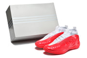 Pair of white and red sneakers pictured beside a plain box.