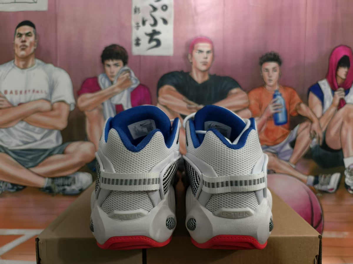 Rear view of white Nike sneakers with blue collar lining, gray heel panels, black patterned side details, and red outsole accents.