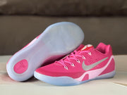 Pink sneakers displayed with one outsole facing upward, showing the translucent traction pattern and Kobe emblem.