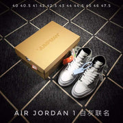Pair of grey and white high-top sneakers beside a tan box, with AIR JORDAN 1 text and a visible size list above.