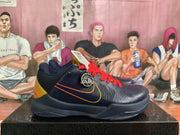 Side view of a navy basketball sneaker showing red laces, orange accent lines, a Nike Swoosh, perforated panels, and a dark outsole.