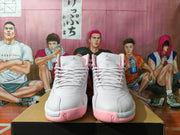 Front view of white and pink high-top sneakers with white laces, Jumpman tongue logos, and textured toe panels.