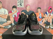 Front view of black high-top basketball sneakers with gold-colored tongue logos and glossy toe overlays.