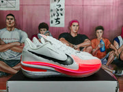 Side profile of a white Nike GT basketball shoe with a black Swoosh, pink accents, and speckled midsole.