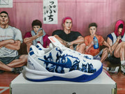 Side view of a white Nike basketball shoe with blue Swoosh branding, blue outsole, and dark blue upper graphics.