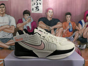 Side profile of cream Nike basketball shoes with black trim and pale pink Swoosh-style accents.
