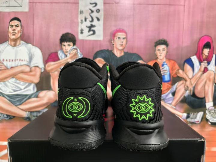 Rear view of black basketball sneakers showing bright green eye graphics on the heel panels and a black outsole.