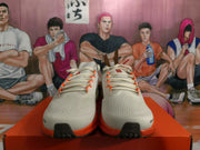 Front view showing the light-colored mesh-style uppers, cream laces, and bright orange outsole accents.