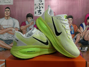 Angled view of paired green Nike sneakers displaying the black Swoosh, white laces, and bright green soles.