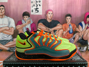 Side profile showing the fluorescent green upper, orange-edged dark teal panels, black midsole, and orange outsole.
