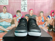 Front view of black lace-up basketball sneakers showing the textured uppers and white toe outsoles.