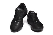 Pair of black Nike-marked low-top sneakers shown from the front, with lace-up fastening and perforated forefoot overlays.