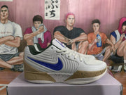 Side profile highlighting the layered white upper, blue Swoosh and textured tan outsole detailing.
