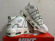 Angled view of white Nike sneakers with oversized AIR lettering and green details