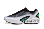 Side view of a white and black Nike Air Max sneaker with green accents and visible circular heel details.