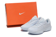 White Nike basketball shoes displayed beside an orange Nike shoe box.