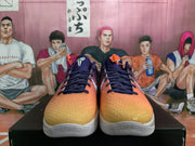 Front view showing the orange textured forefoot, navy laces, dark upper, and white outsoles.