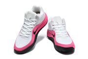 Angled front view showing the white mesh-like upper, pink overlays, black swoosh, and lace-up construction.