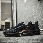 Black and gold Nike TN-11 sneakers shown in side view