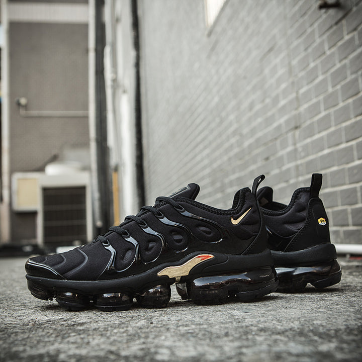 Black and gold Nike TN-11 sneakers shown in side view