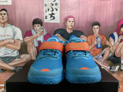 Front view of blue basketball-style sneakers with orange straps, blue laces, and mesh uppers.